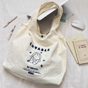 Detail of canvas tote bag showing navy bunny print and secure black snap button closure