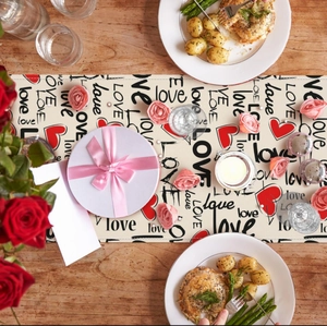 Detail of a Valentine table runner with red hearts and LOVE print on a wooden dining table