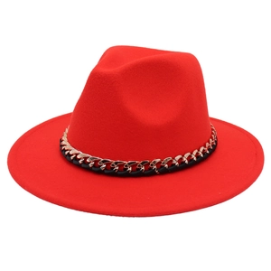 Detailed view of red fedora hat featuring a decorative gold chain and black ribbon band