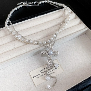 Détail du pendentif croix à texture baroque et perles sur collier à double rang