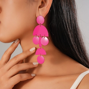Dettaglio di orecchini geometrici rosa acceso con pendenti circolari e rettangolari a strati