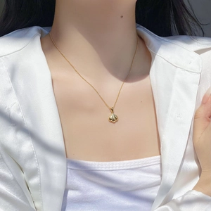 Close-up of a minimalist gold heart pendant necklace worn with a white silk shirt