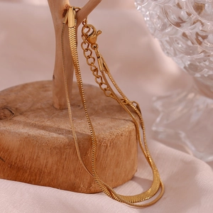 Detail view of double-layer gold snake chain bracelet with lobster clasp and adjustable tail