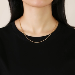 Close-up of a 2mm gold stainless steel snake chain necklace worn by a model