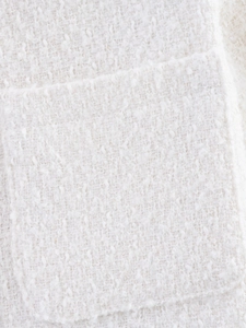 Macro della trama in tweed bianco crema e dei dettagli della tasca della giacca elegante