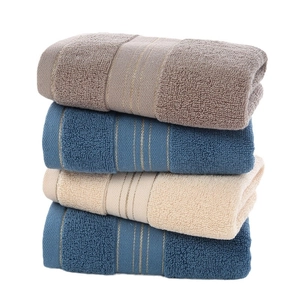 Set of four premium absorbent cotton towels in brown, navy, and beige with soft texture