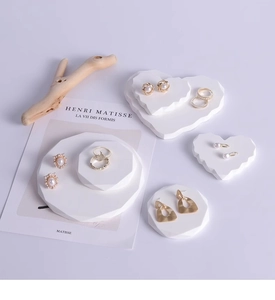 Detailed close-up of golden jewelry collection displayed on white geometric gypsum pedestals