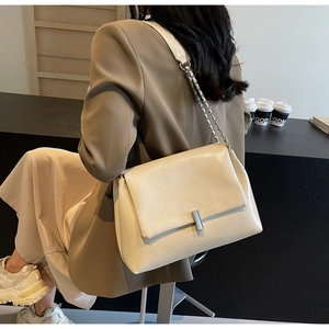 Detail of off-white vintage tote with metal lock and chain strap in cafe setting