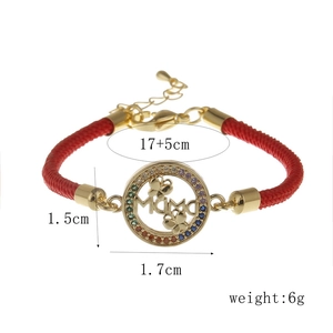 Détail du bracelet en cordon rouge avec pendentif MAMA doré et zircons colorés