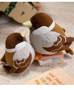 Close-up of two cute bird plush toys in small and large sizes on a soft white rug