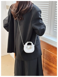 Rear view of model wearing white saddle bag with silver metal ring handle and chain