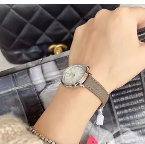 Detail of elegant ladies watch with diamond bezel, grey leather strap on woman wrist