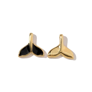 Detailed close-up of whale tail pendants in gold finish and black enamel texture