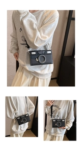Detail of creative camera-shaped crossbody bag featuring a vintage lens and flash design