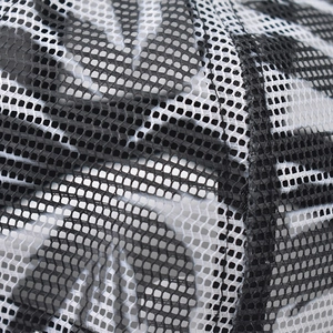 Détail macro du tissu en maille noire respirante avec motif palmier sur casquette