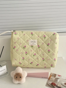 Detail of yellow quilted makeup bag featuring purple tulip pattern and zipper closure