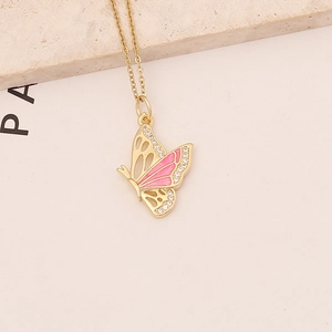 Golden butterfly necklace with pink enamel and zircon inlay on a textured beige stone base
