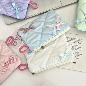 Macro shot of quilted makeup pouches in pastel colors with decorative bow detail