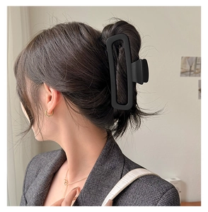Close-up of a matte black rectangular hollow hair claw clip worn on a woman's hair