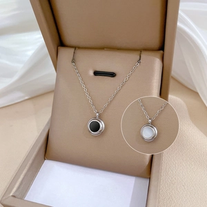 Detail of double-sided shell pendant necklace with black and white inlay in a jewelry box