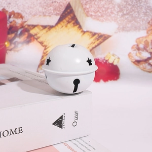 Gros plan d'une cloche de Noël en métal blanc avec étoiles découpées sur un livre