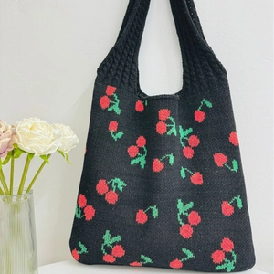Knitted tote bag with cherry pattern and red handles on a clean white background