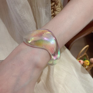 Detailed close-up of iridescent acrylic bangle with irregular geometric design