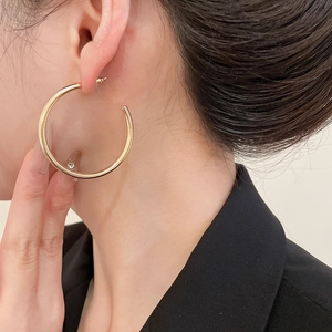 Close-up of model wearing high-shine gold C-shaped twisted hoop earrings for women