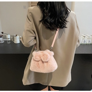 Nahaufnahme der rosa Plüsch-Beuteltasche mit Kunstpelz-Textur und Lederriemen am Modell