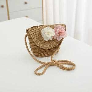 Detailed macro view of a child's straw crossbody bag with white and pink fabric flowers