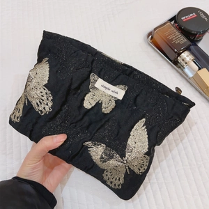 Vintage Make-up Tasche mit Schmetterlingsmuster und Logo auf weißer gesteppter Bettwäsche