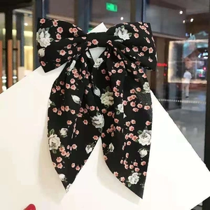 Detail of large bow hair clip with pink floral pattern on black chiffon fabric