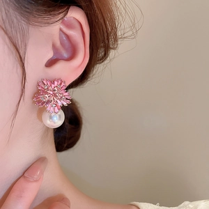 Detail of pink crystal flower earrings with a large white pearl drop on female ear