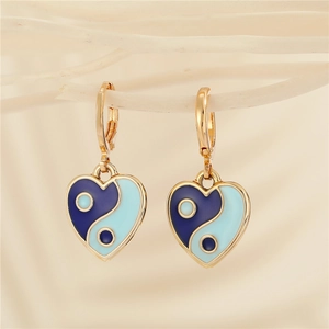 Macro detail of heart-shaped yin yang earrings with blue enamel in gold finish