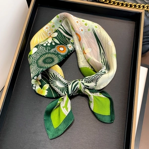 Elegant silk floral scarf in green and yellow print displayed on a black tray