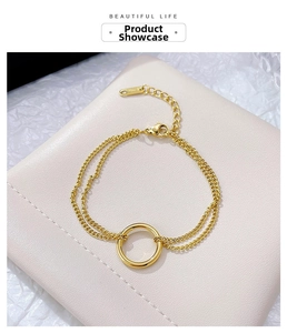 Detail of a double-layered gold chain bracelet with round circle pendant on beige display