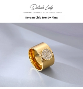 Detailed close-up of wide gold fashion ring with micro-set zircon disc on textured surface