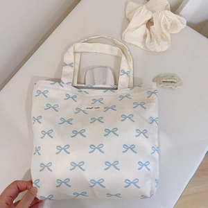 Detail of blue bow pattern on white canvas tote bag with simple wish label