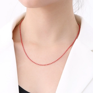 Detailed close-up of a delicate red beaded chain necklace on a model's collarbone