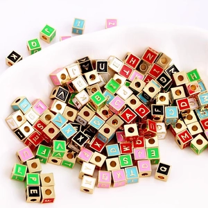 Macro detail of colorful enamel alphabet beads in a white bowl for DIY jewelry