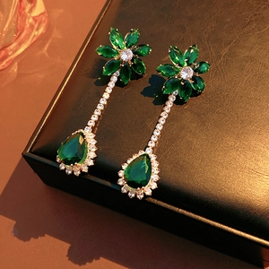 Detail of elegant green flower and teardrop zircon drop earrings on a black leather box