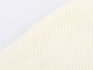 Nahaufnahme von cremeweißem Strickkleid mit Rippenstruktur und Pelzbesatz an den Ärmeln