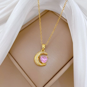 Detail of gold crescent moon necklace with pink heart gem in elegant gift box