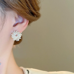 Close-up of elegant silver flower cluster earrings with zircon and pearls on model