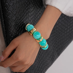 Dettaglio di perline turchesi marmorizzate e distanziatori dorati su bracciale