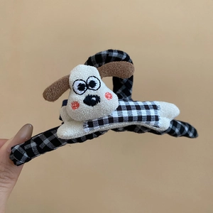 Détail d'une pince à cheveux teckel en peluche avec un ornement de nœud à carreaux noir et blanc