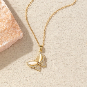 Detail of gold butterfly necklace featuring cat eye stone and sparkling white zircon wings
