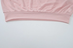 Detail of pink knitted top showing elastic ribbed hem and premium fabric texture