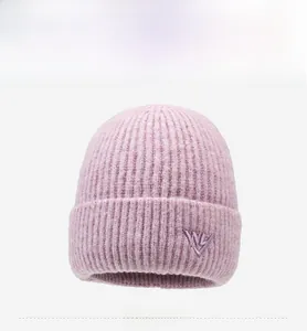 Close-up of pink knit beanie with purple letter W embroidery and thick cuffed brim