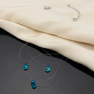 Detailed view of teal teardrop glass pendants on invisible fishing line necklaces